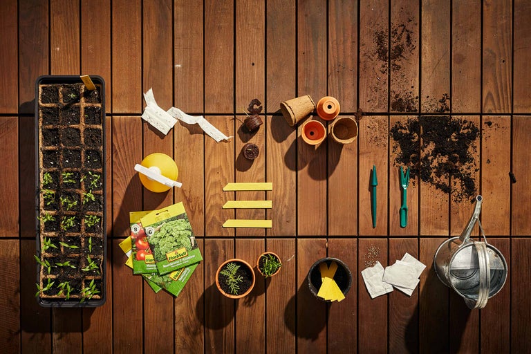 Zaaiscène met plantenbakken, zaden en tuingereedschap op houten tafel