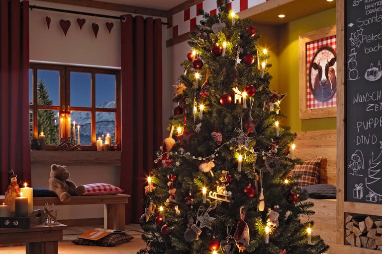 Feestelijk versierde kerstboom met lichtjes en decoratie in een gezellige woonkamer.