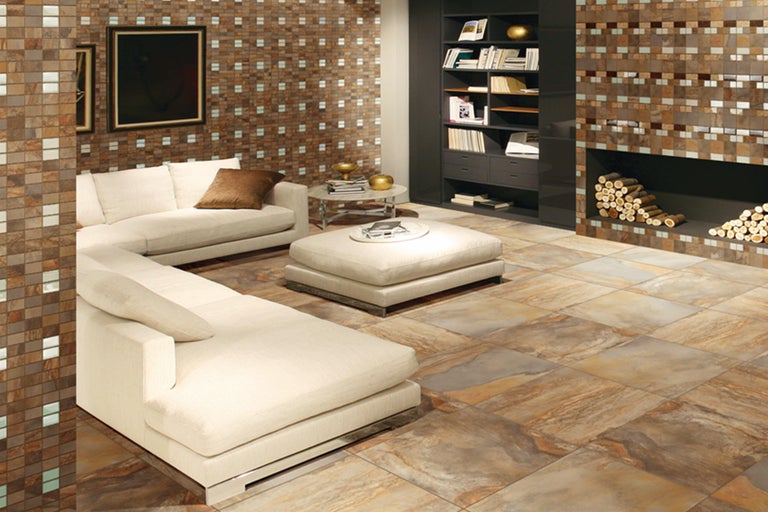 Lichte woonkamer met bank, fauteuil, boekenkast en tegelvloer