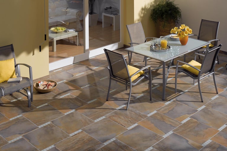 Terras met tafel, stoelen en vloertegels in warme kleuren