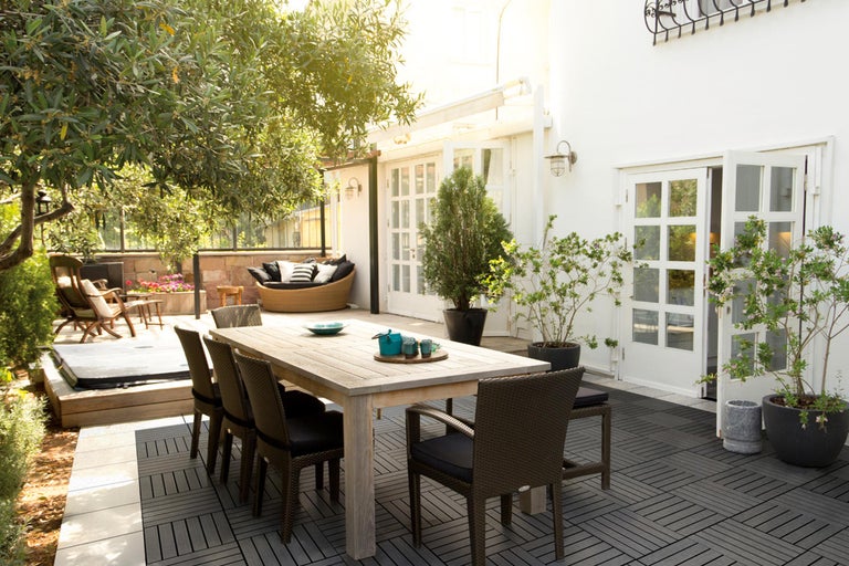 Buitenscène met houten terras, eettafel met stoelen en een zithoek
