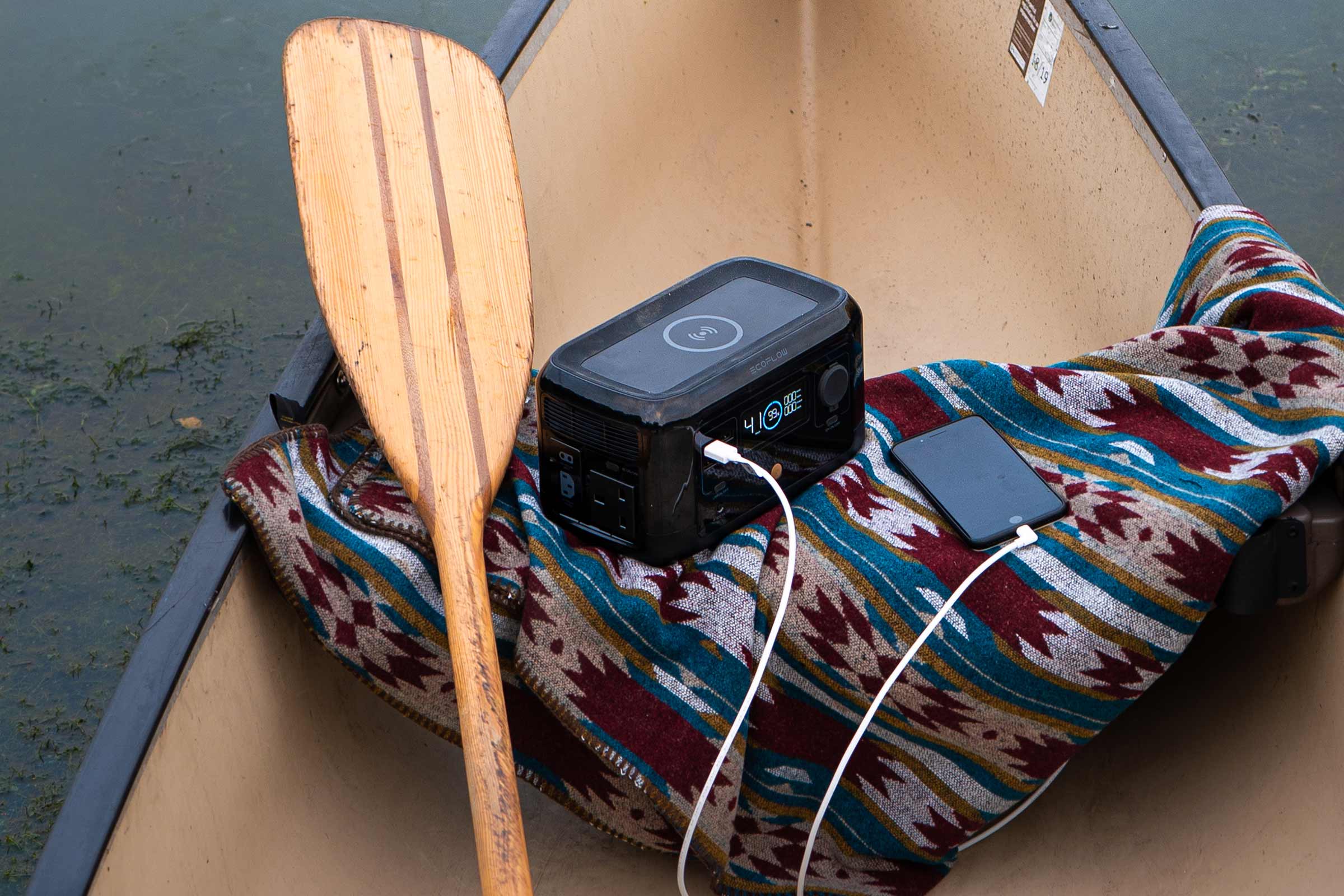 Energieopslagapparaat met peddel en mobiele telefoon in een kano