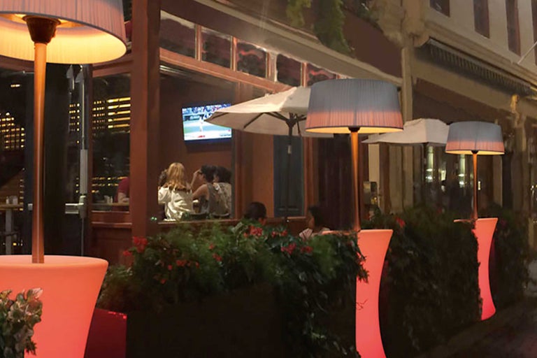 Restaurantterras met verlichte staande lampen en plantenbakken