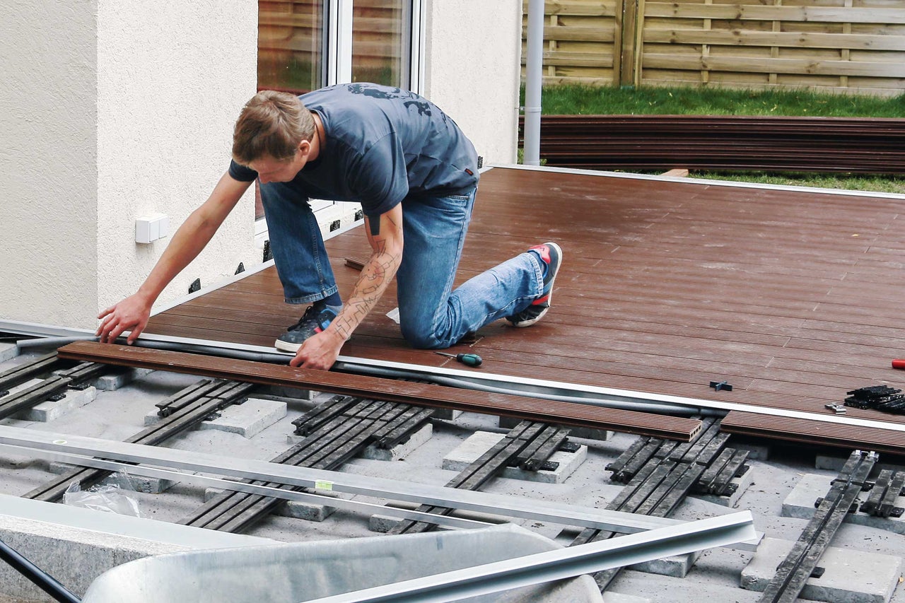 Man legt terrasplanken op een onderconstructie buiten.