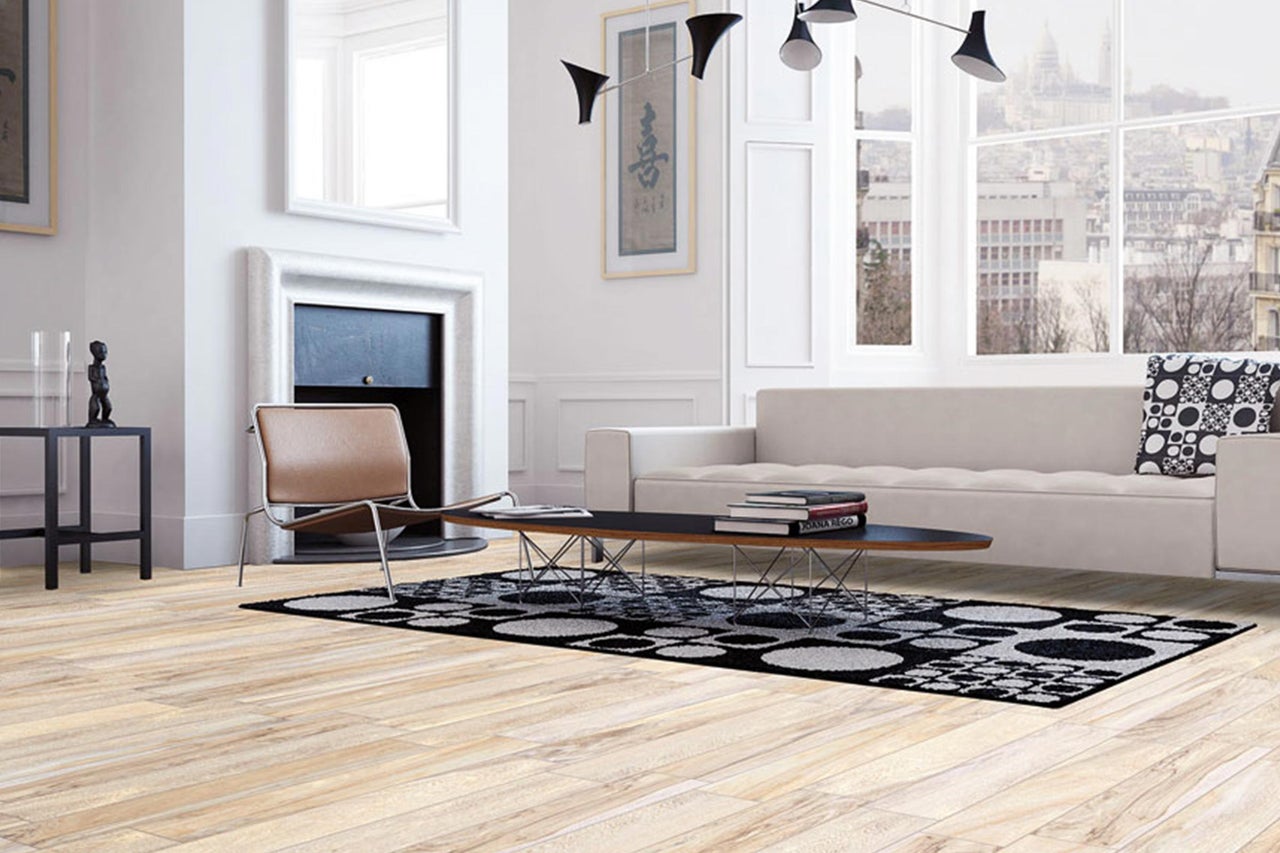 Lichte woonkamer met bank, fauteuil, vloerkleed en houten vloer