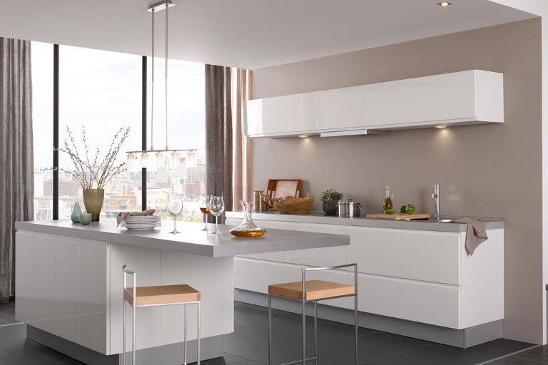 Lichte, moderne keuken met kookeiland, zitplaatsen, ramen en decoratieve elementen.