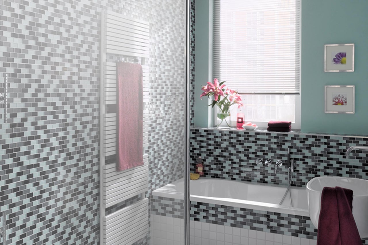 Badkamer met mozaïektegels, bad en handdoekradiator