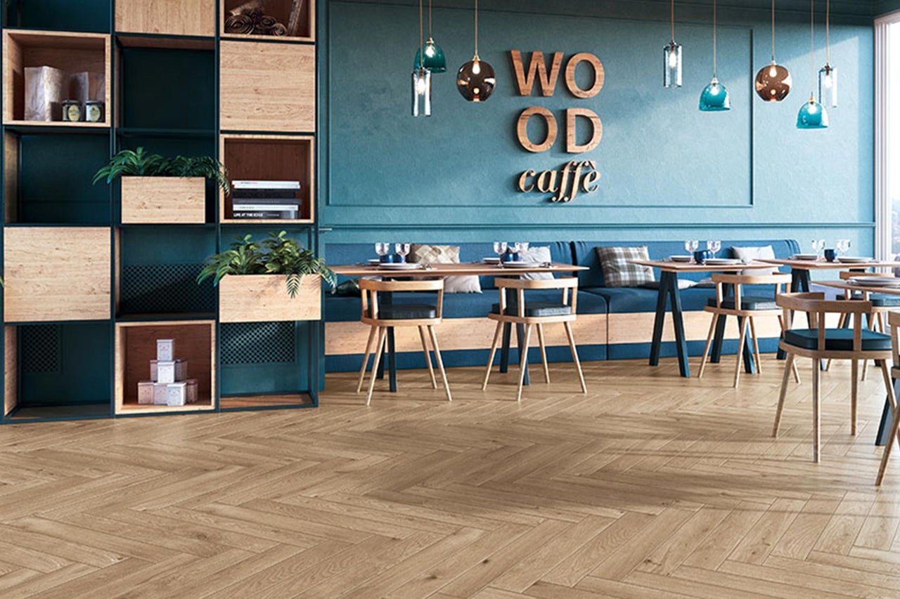 Interieur van een café met houten vloer in visgraatmotief, tafels, stoelen en een rek