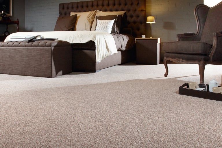 Slaapkamer met tapijt, bed, nachtkastje en fauteuil