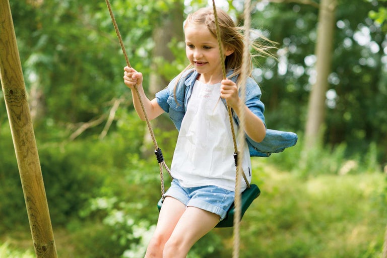 Meisje schommelt op een touwschommel in de tuin