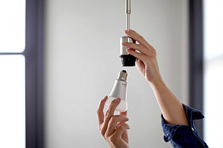 Iemand schroeft een ledlamp in een lampfitting.