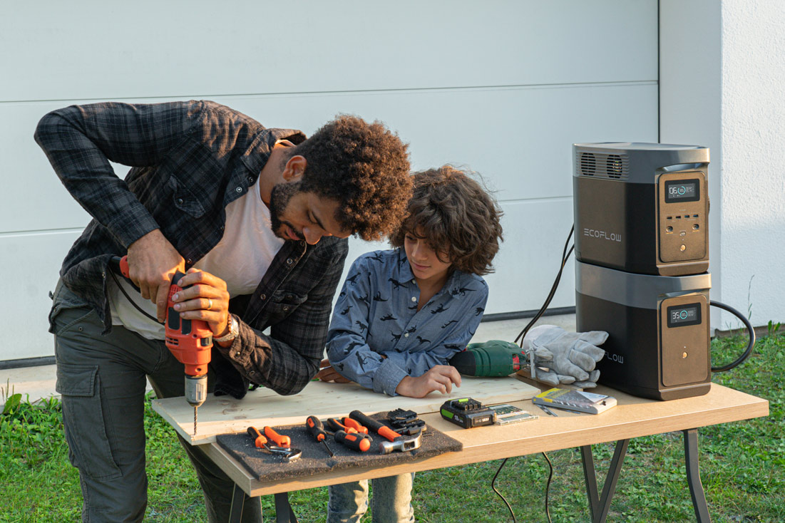 Vader boort met zijn zoon een gat in een plank op een tafel, met EcoFlow Powerstation