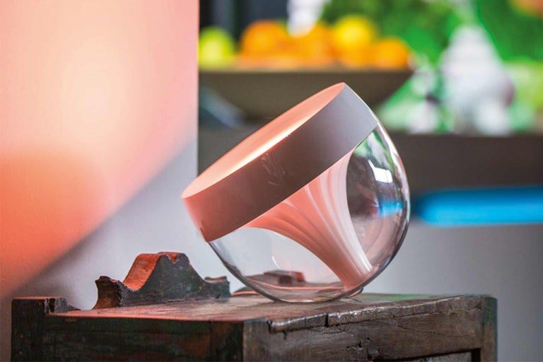 Philips Hue Iris tafellamp van glas op een houten tafel
