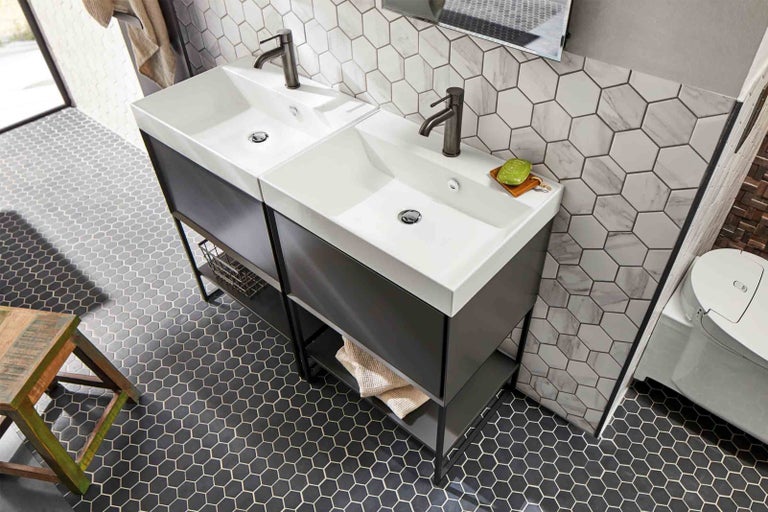 Badkamer met twee wastafels, zeshoekige tegels en houten kruk
