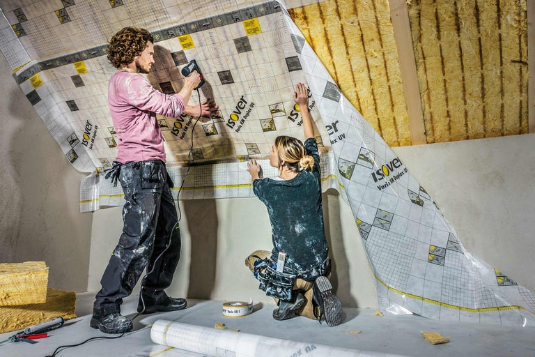 Twee personen bevestigen een Isover dampschermfolie aan een schuin dak.