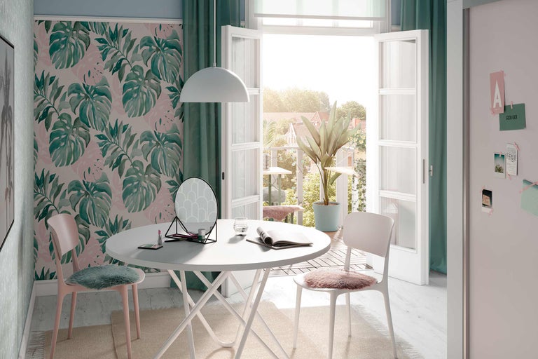 Lichte kamer met Monstera-behang, witte tafel, stoelen, spiegel en decoratie voor een vriendelijke sfeer.