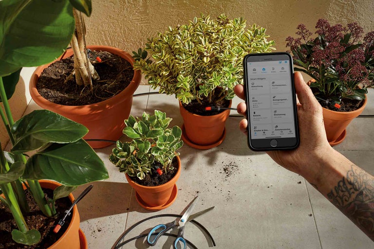 Plantenbesproeiingssysteem met smartphone app bediening in een heldere kamer