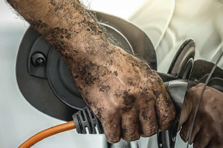 Een vuile hand sluit een elektriciteitskabel aan op een elektrisch apparaat