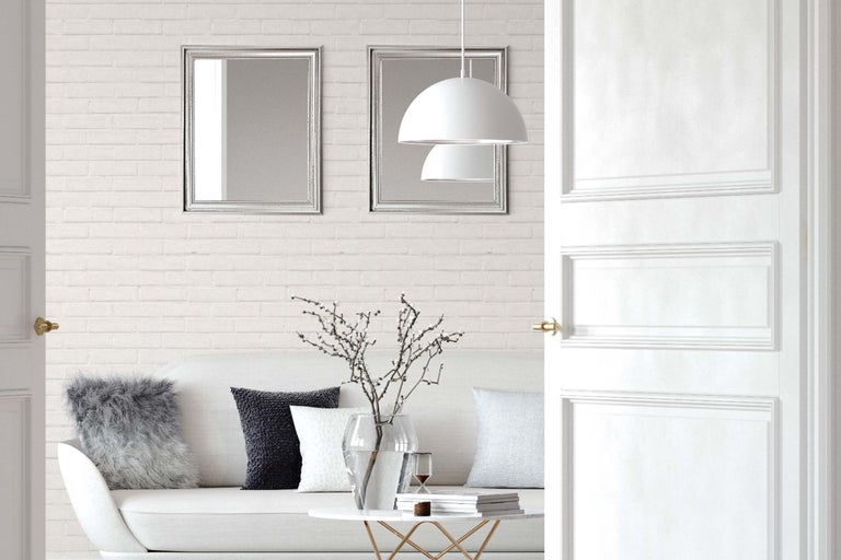 Lichte woonkamer met bank, tafel, decoratie, twee spiegels, een hanglamp en een openstaande deur