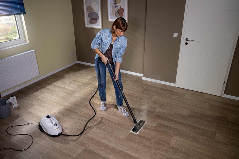 Vrouw reinigt vloer met stoomreiniger in een kamer met houten vloer