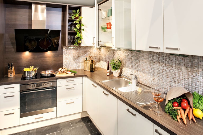 Keukenoverzicht met spoelbak, kookplaat, oven, afzuigkap en keukengerei.