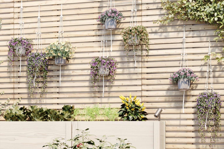 Decoratieve tuinscène met houten plantenwand en hangende bloempotten.