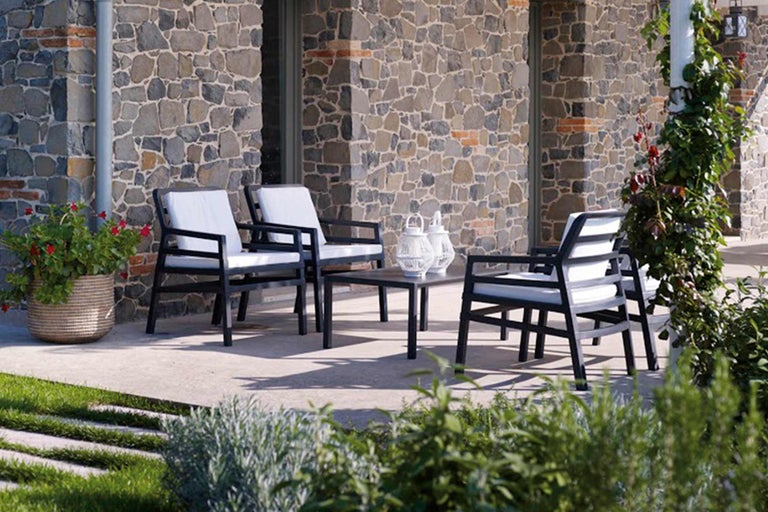 Tuinmeubelset met tafel en stoelen op terras voor stenen muur