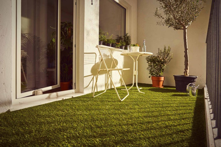 Balkon met kunstgras, stoel, tafel en planten