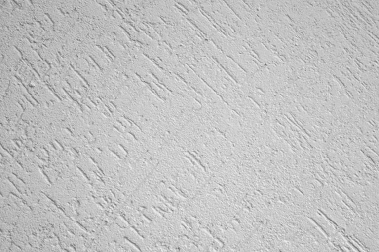 Gedetailleerd beeld van een muur met een krabpleister textuur.