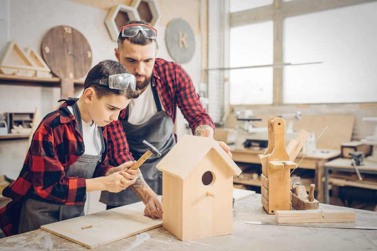Vader en zoon bouwen samen een vogelhuisje in de werkplaats.