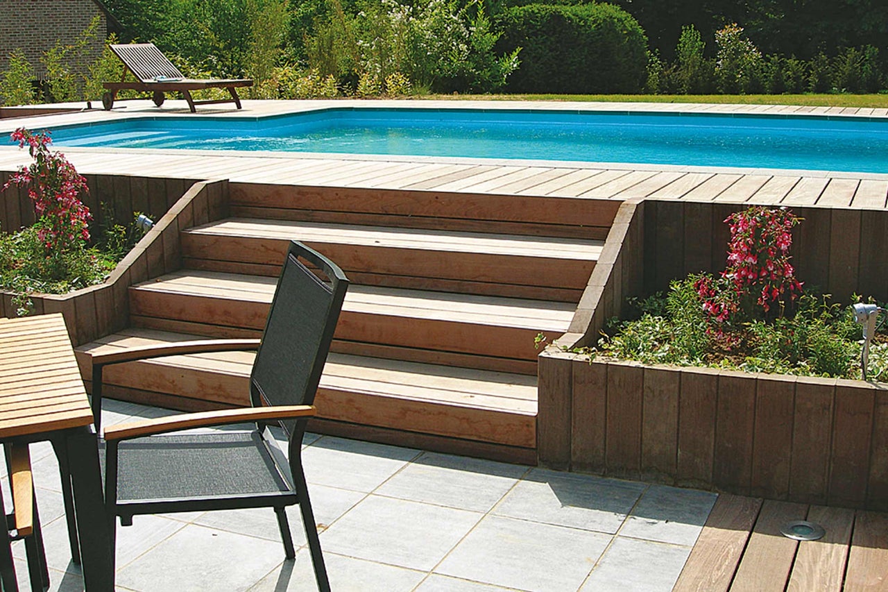 Zwembad met houten terras, trap en tuinmeubelen