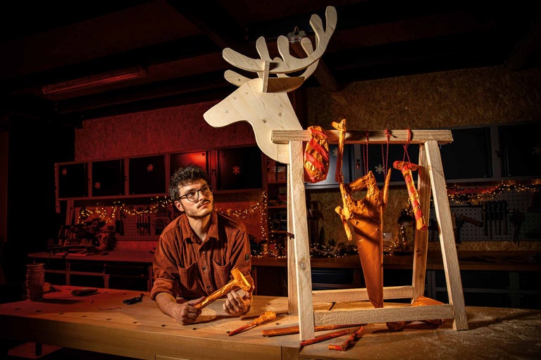 Man kijkt naar houten rendierdecoratie en gereedschap in de werkplaats