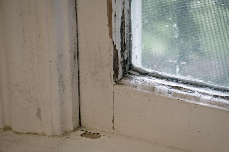 Detailopname van een oud raam met afbladderende verf en beschadigingen