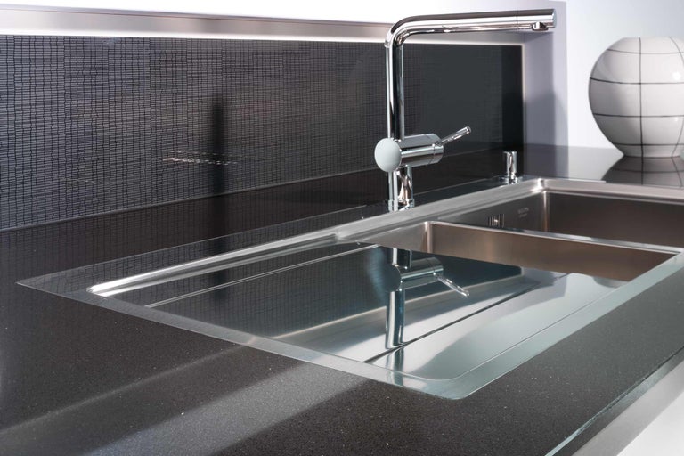 Roestvrijstalen spoelbak met kraan op een donker aanrechtblad