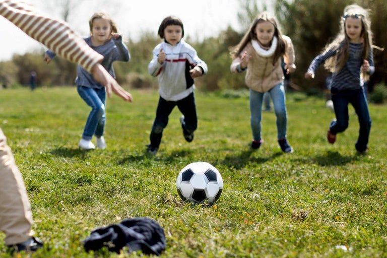 Kinderen spelen voetbal op een grasveld.