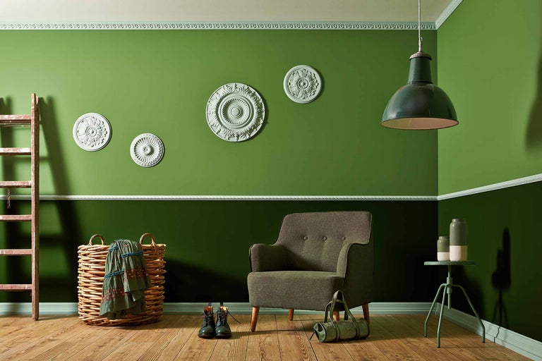 Lichte kamer met groene muren, fauteuil, lamp en decoratieve elementen.