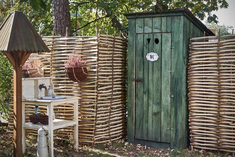 Tuinscène met toilet, wastafel en houten hek