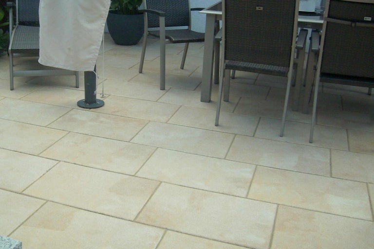 Terrastegels gelegd in een buitenruimte met tuinmeubilair