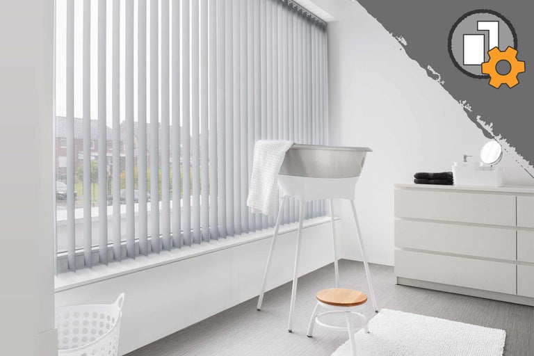 Lichte badkamer met raam, voorzien van jaloezieën, bad, kruk en commode.