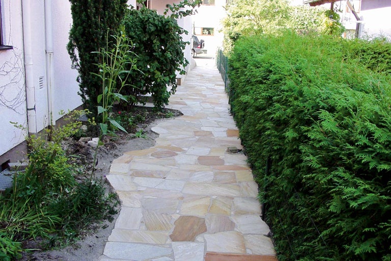 Tuinpad van natuursteenplaten met aangrenzende groene planten