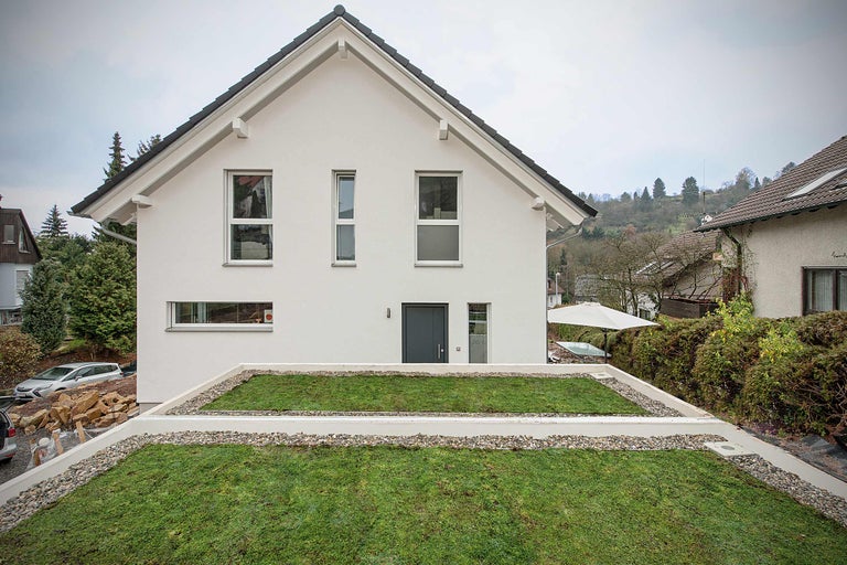 Moderne eengezinswoning met groen plat dak en lichte gevel.