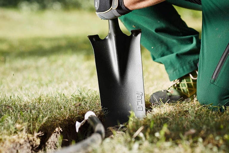 Iemand graaft een gat in de tuin met een spade.
