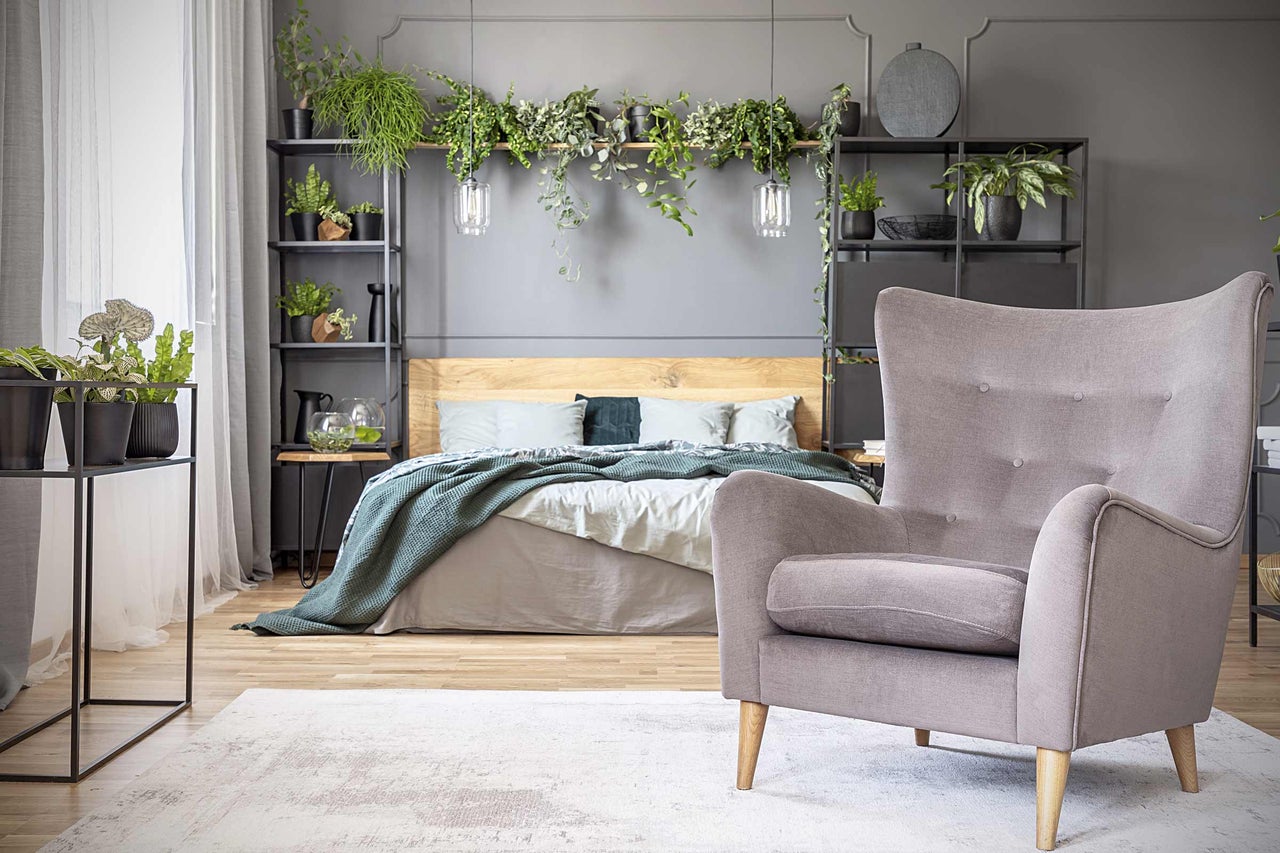 Slaapkamer met bed, fauteuil, planken en kamerplanten
