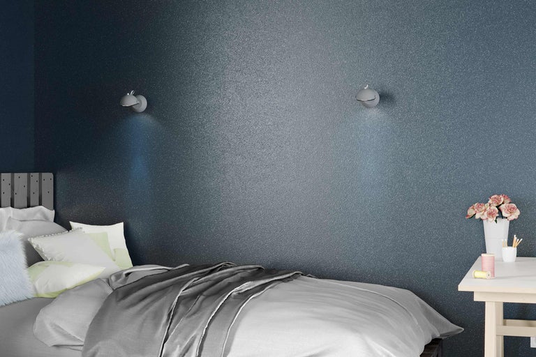 Slaapkamer met bed, nachtkastje en wandlampen voor een gestructureerde muur