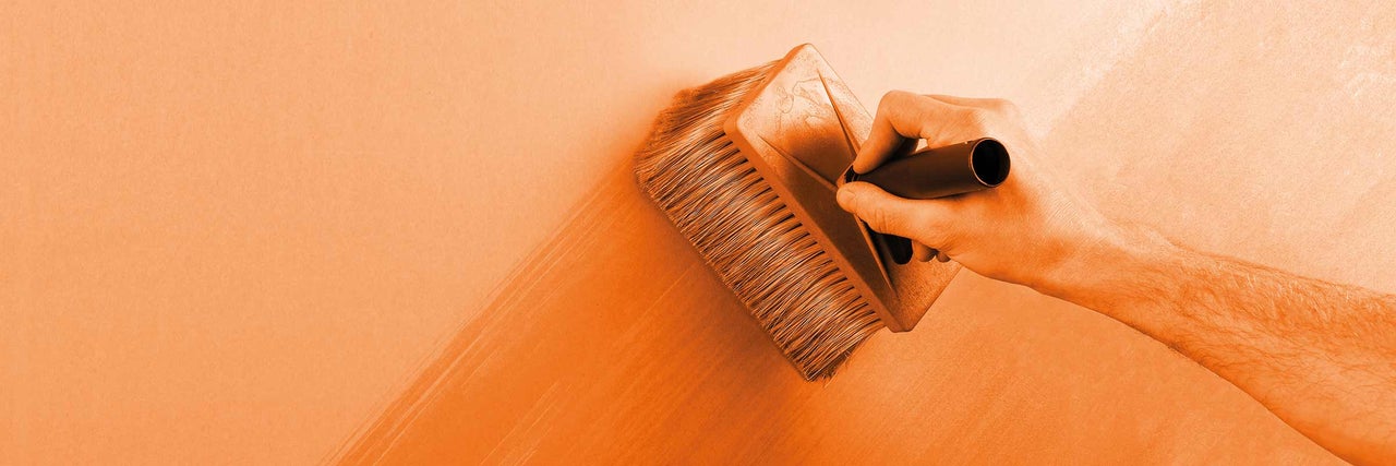 Persoon brengt een verfborstel aan op een muur