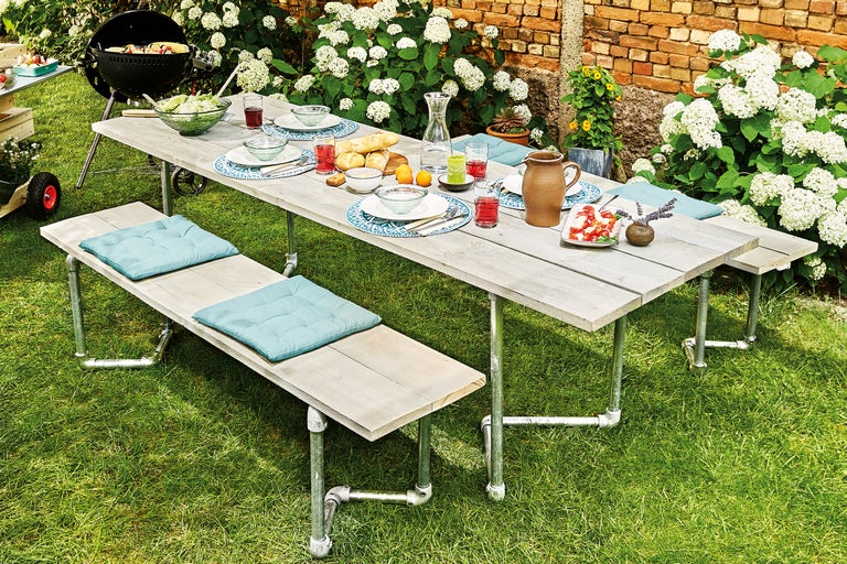 Gedekte eettafel en banken in de tuin met barbecue
