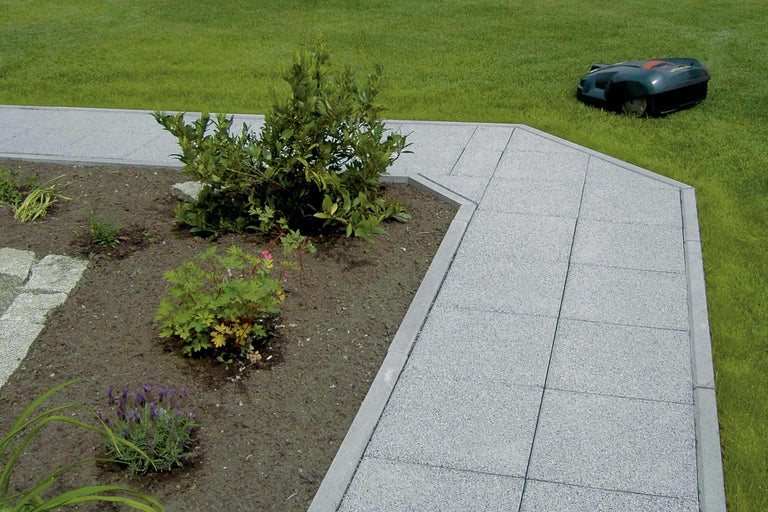 Tuinpad met robotmaaier op de achtergrond