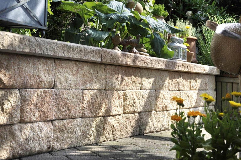 Een tuinmuur van natuursteen met planten en decoratieve elementen