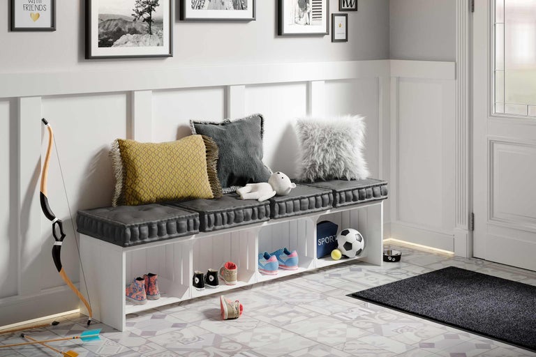 Entree met schoenenbank, kussens en decoratieve artikelen op een vloer met patroon