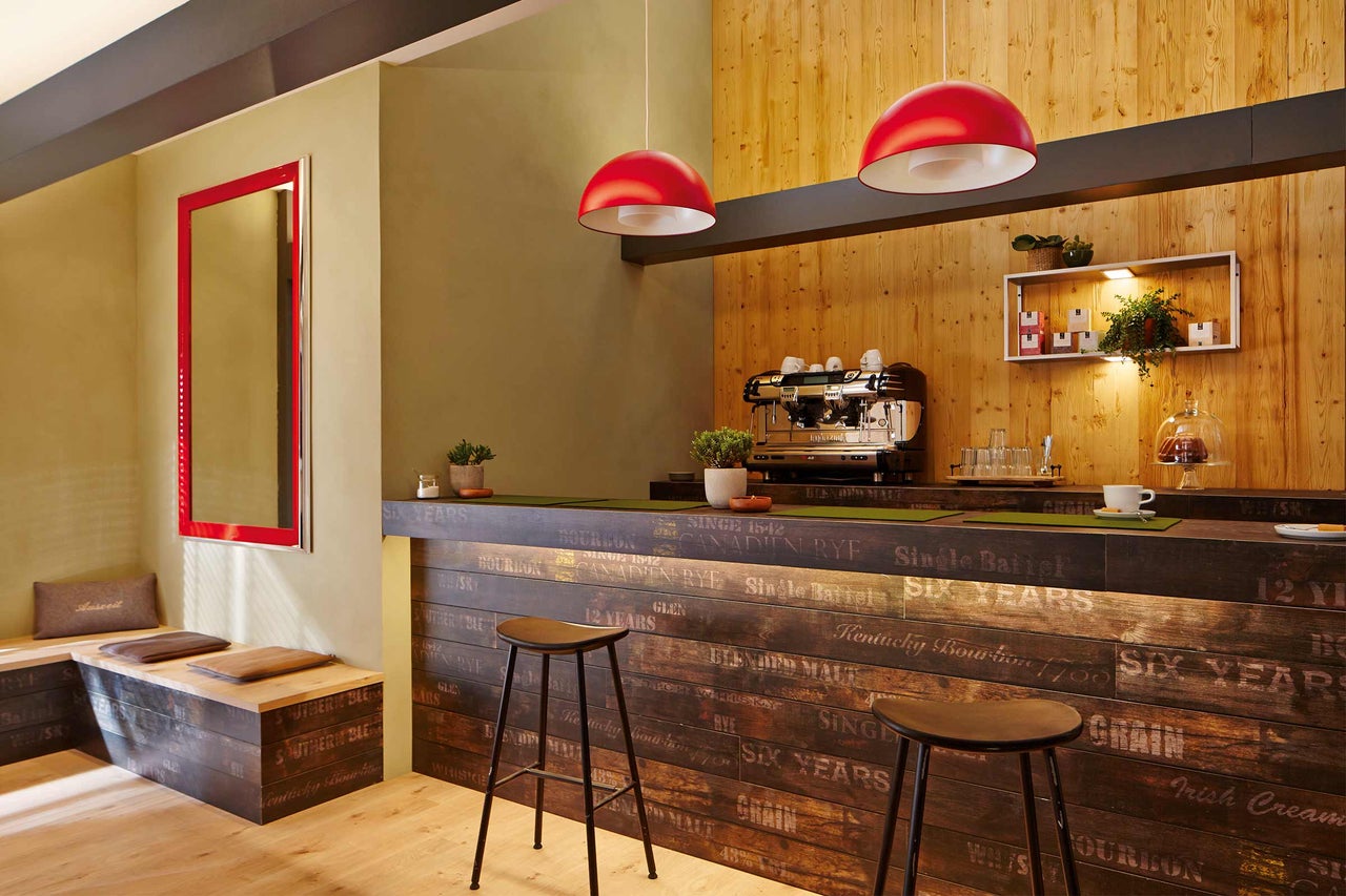 Gastruimte met houten bar, barkrukken en rode verlichting